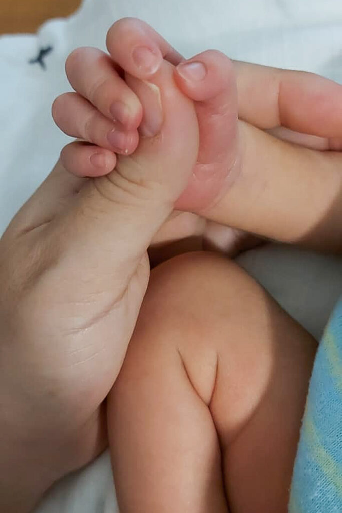 Mother holding the hand of baby scʕasxəń Shale Clayton. Image courtesy of Rheana Marchand