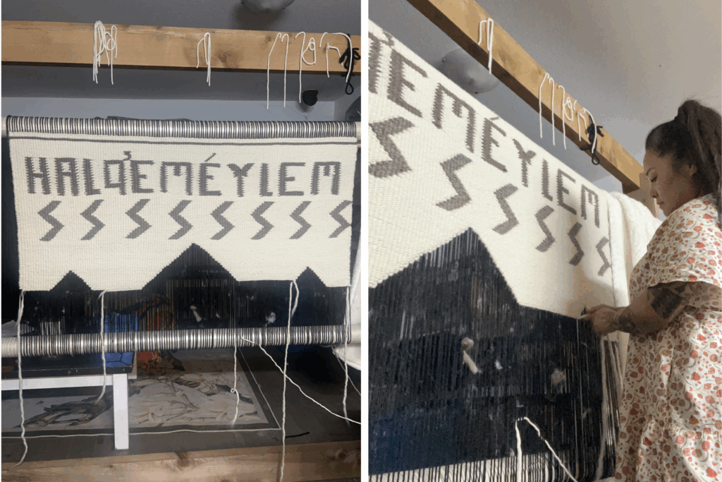 Salish weaver Joy Hall workng on a weaving project. She stands at a loom working with the wool. The wool includes the text Halq'eméylem for the name of her language.